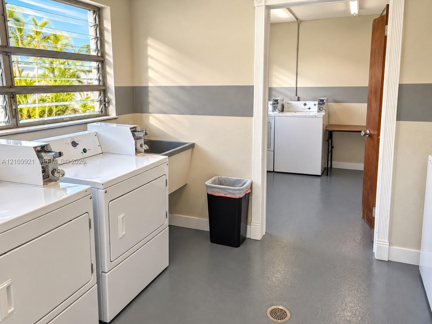 Utility room featuring jalousie windows, a deep basin sink, and resilient epoxy-coated flooring