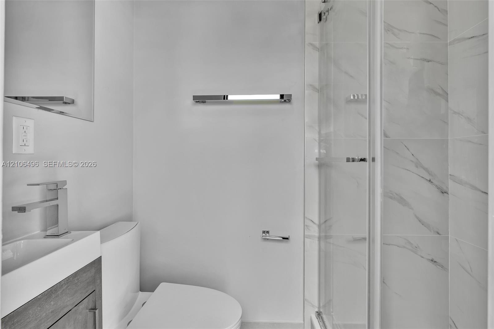 Modern bathroom featuring a wood-finish vanity, rectangular vessel sink with a polished chrome faucet, glass-enclosed shower with tiled walls, and pol