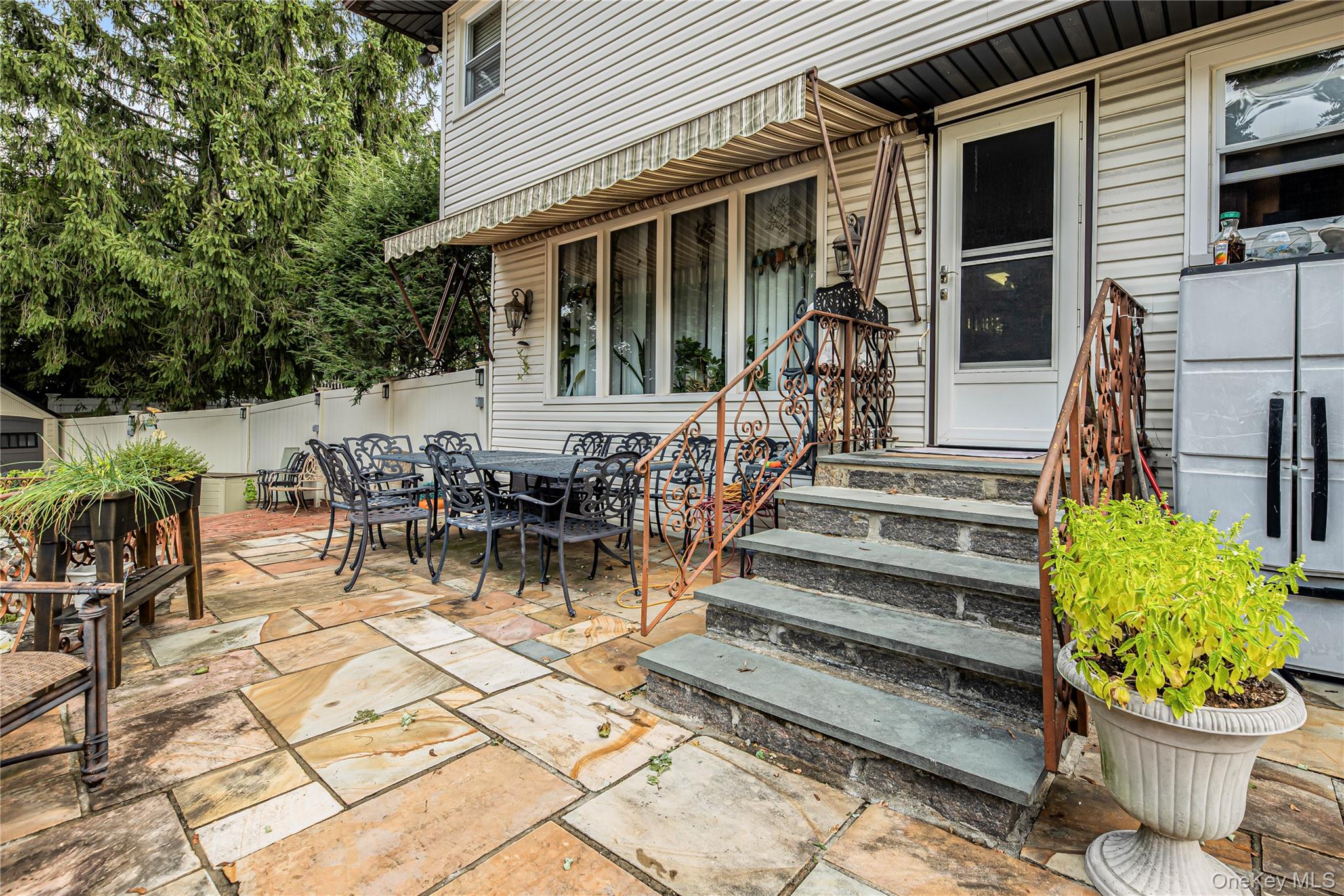 Expansive stone patio with natural stone steps and wrought iron railings