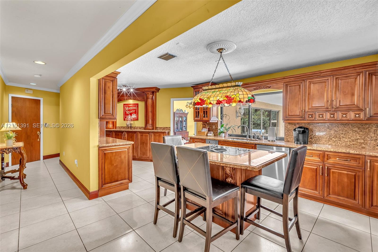 Kitchen featuring a central island, wood cabinetry, stone countertops, and tile flooring