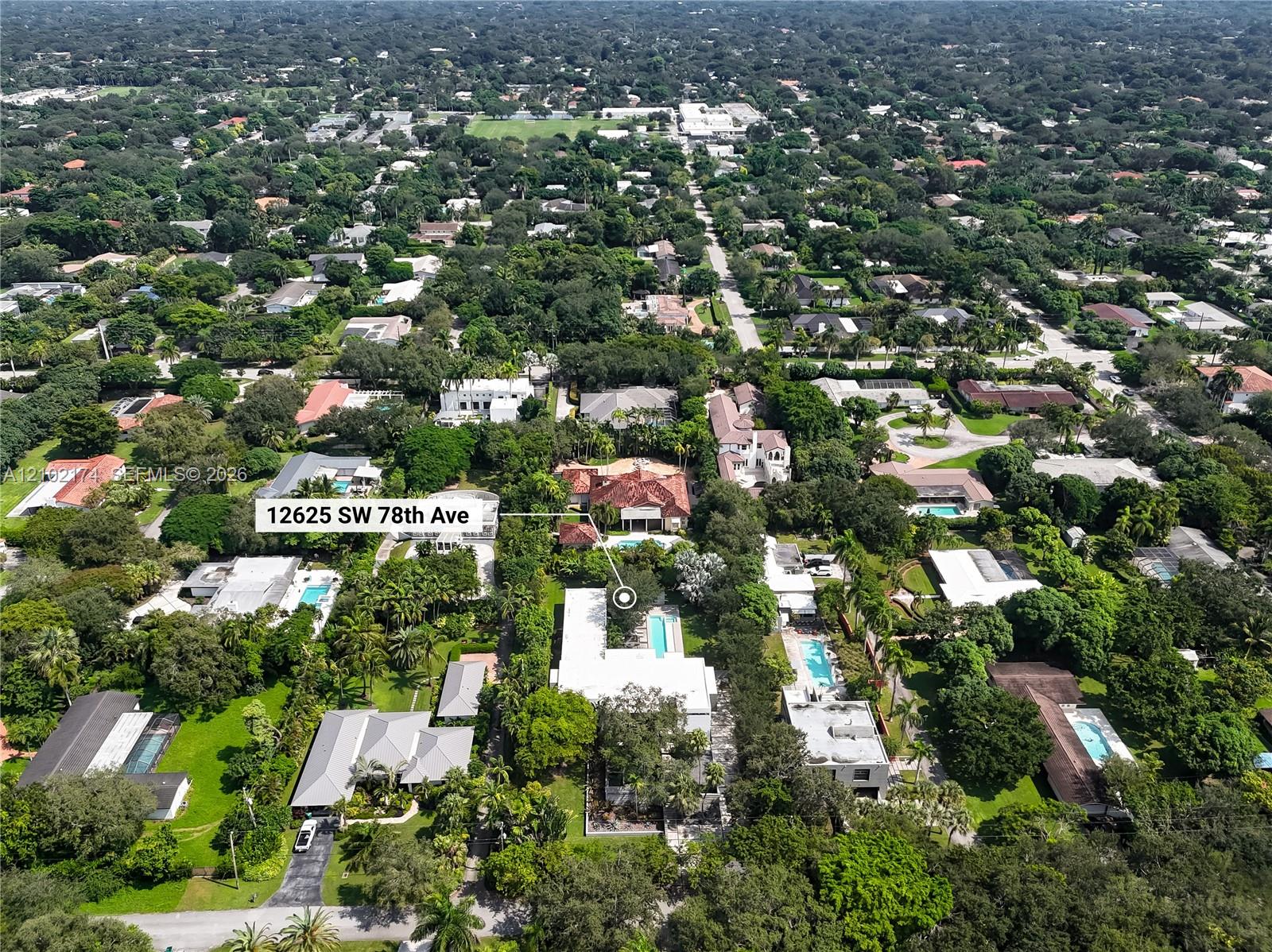 Aerial view of the property featuring a rectangular swimming pool, expansive green space, mature landscaping, and a multi-section roofline