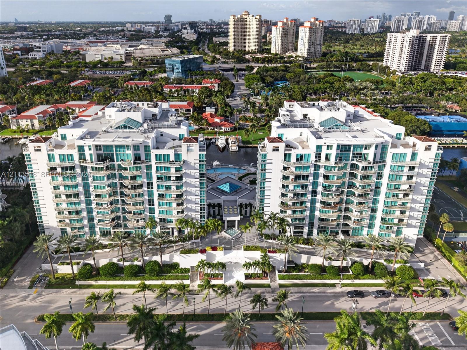 High-rise waterfront residential complex featuring private balconies, an on-site swimming pool, deep-water boat slips, and extensive perimeter landsca