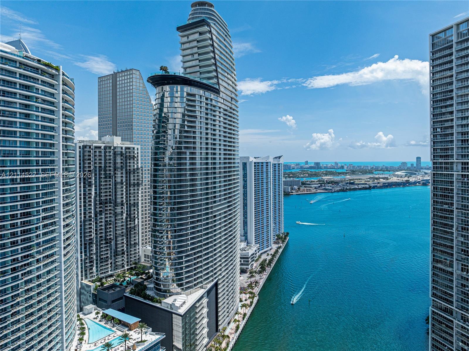 High-rise architectural structure featuring a glass facade, curved balconies, and direct water frontage on the harbor
