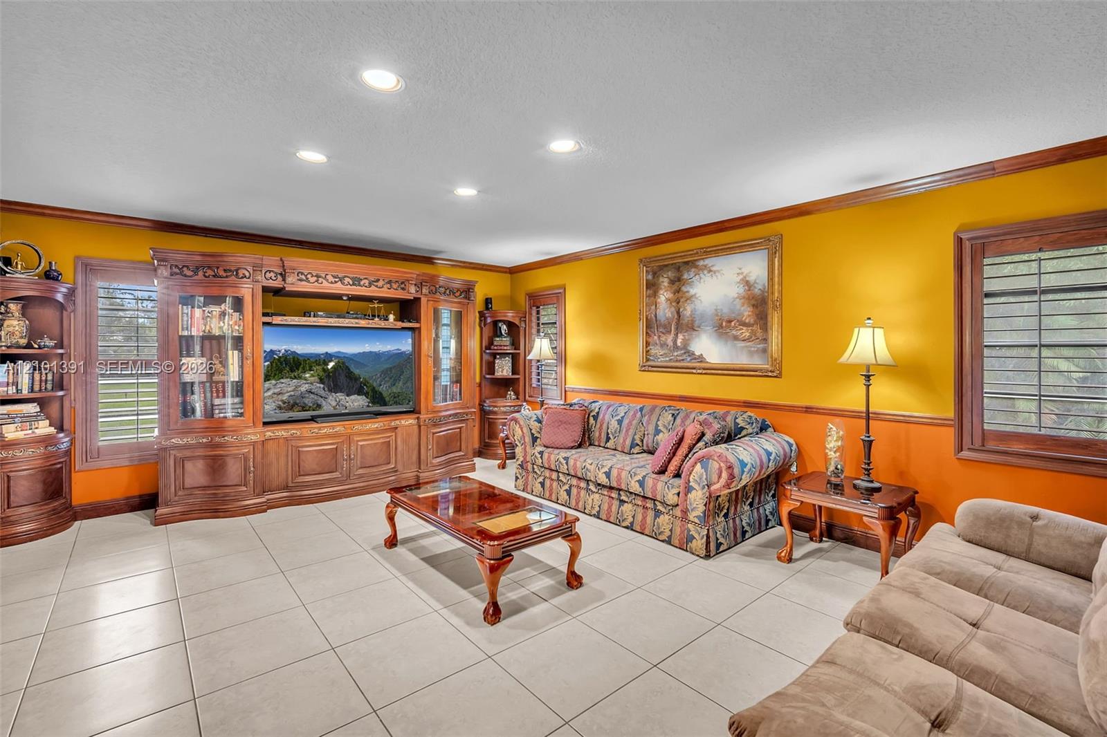 Recessed lighting illuminates the room, featuring tile flooring and crown molding