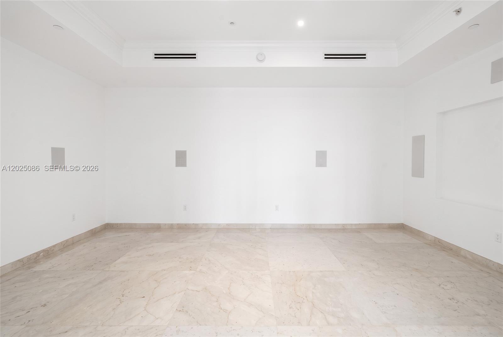 Tray ceiling with recessed lighting, stone flooring, and integrated wall-mounted speakers