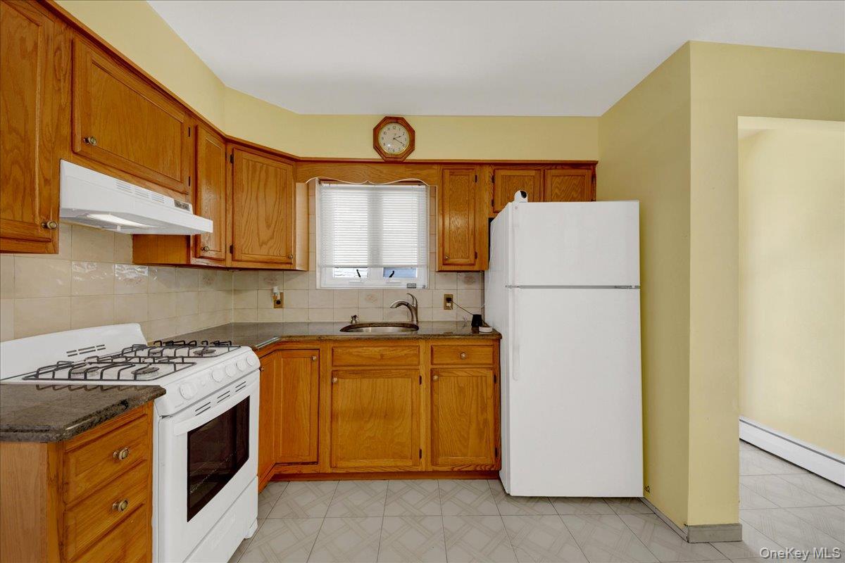 Kitchen in the 2 BR unit, featuring wood cabinets and white updated appliances