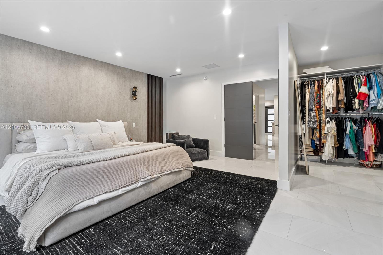 Bedroom featuring tile flooring, recessed lighting, a textured accent wall with vertical slat detailing, and an open-concept built-in closet system