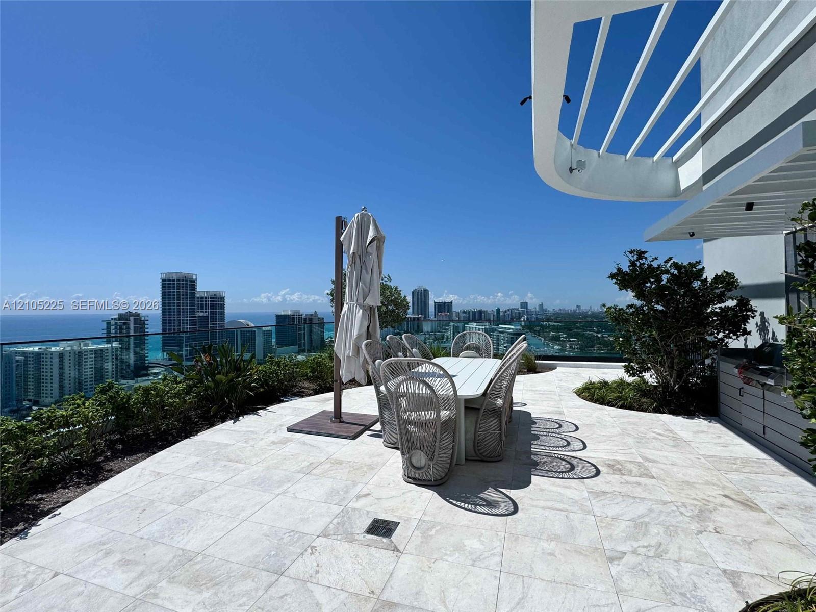 Expansive outdoor terrace featuring paver flooring, a perimeter glass railing, and integrated landscaping