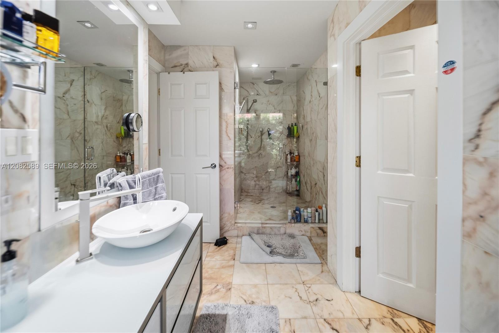 Spa-inspired primary bathroom with marble finishes and a walk-in glass shower.