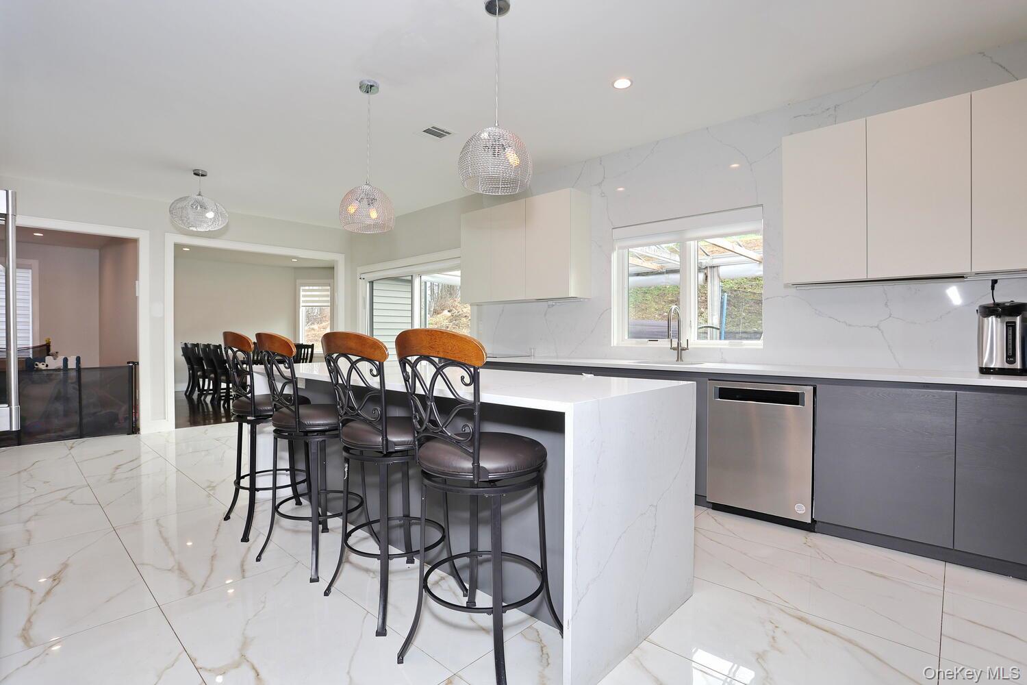 Kitchen featuring a kitchen bar, light marble finish floors, decorative light fixtures, white cabinets, and recessed lighting