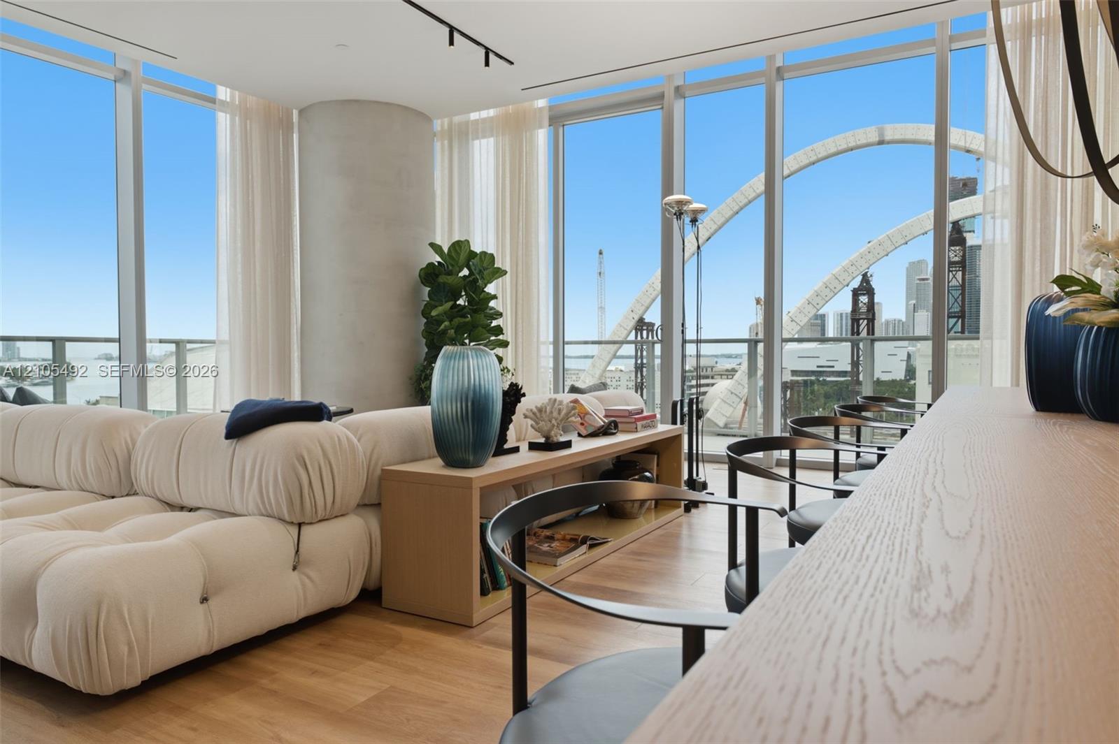 Floor-to-ceiling windows, wood-finish flooring, exposed concrete column, track lighting, and private balcony
