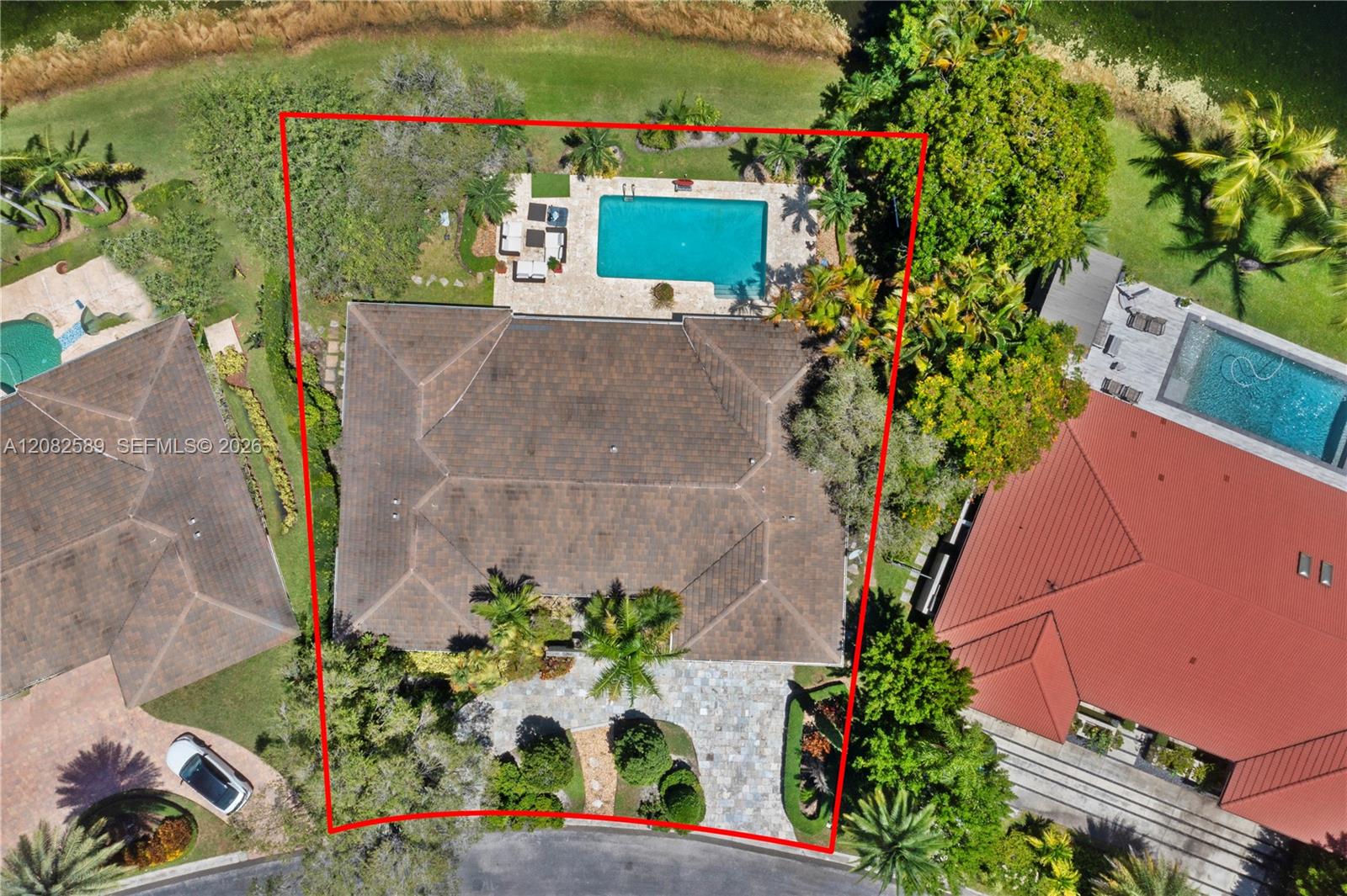 Top-down aerial view highlighting the property’s generous lot, private pool, landscaped grounds, and lake setting.