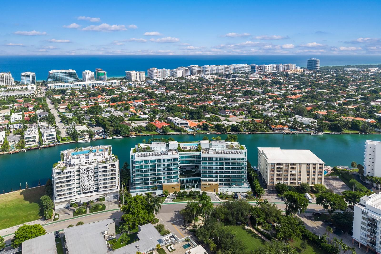 Aerial perspective of a multi-story waterfront residential building featuring floor-to-ceiling glass paneling, private balcony terraces, and rooftop a