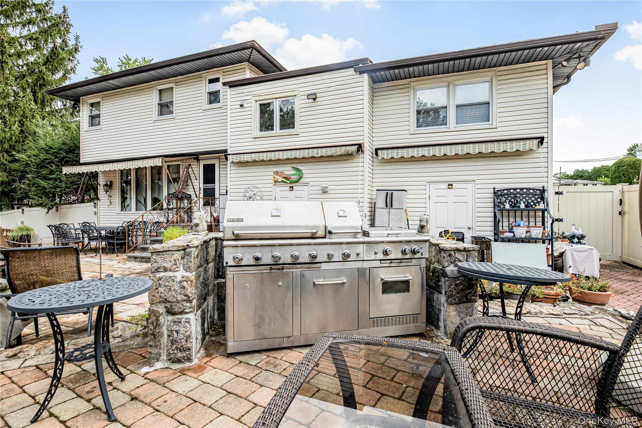 Expansive stone patio featuring a stone-faced raised planter and white privacy fencing