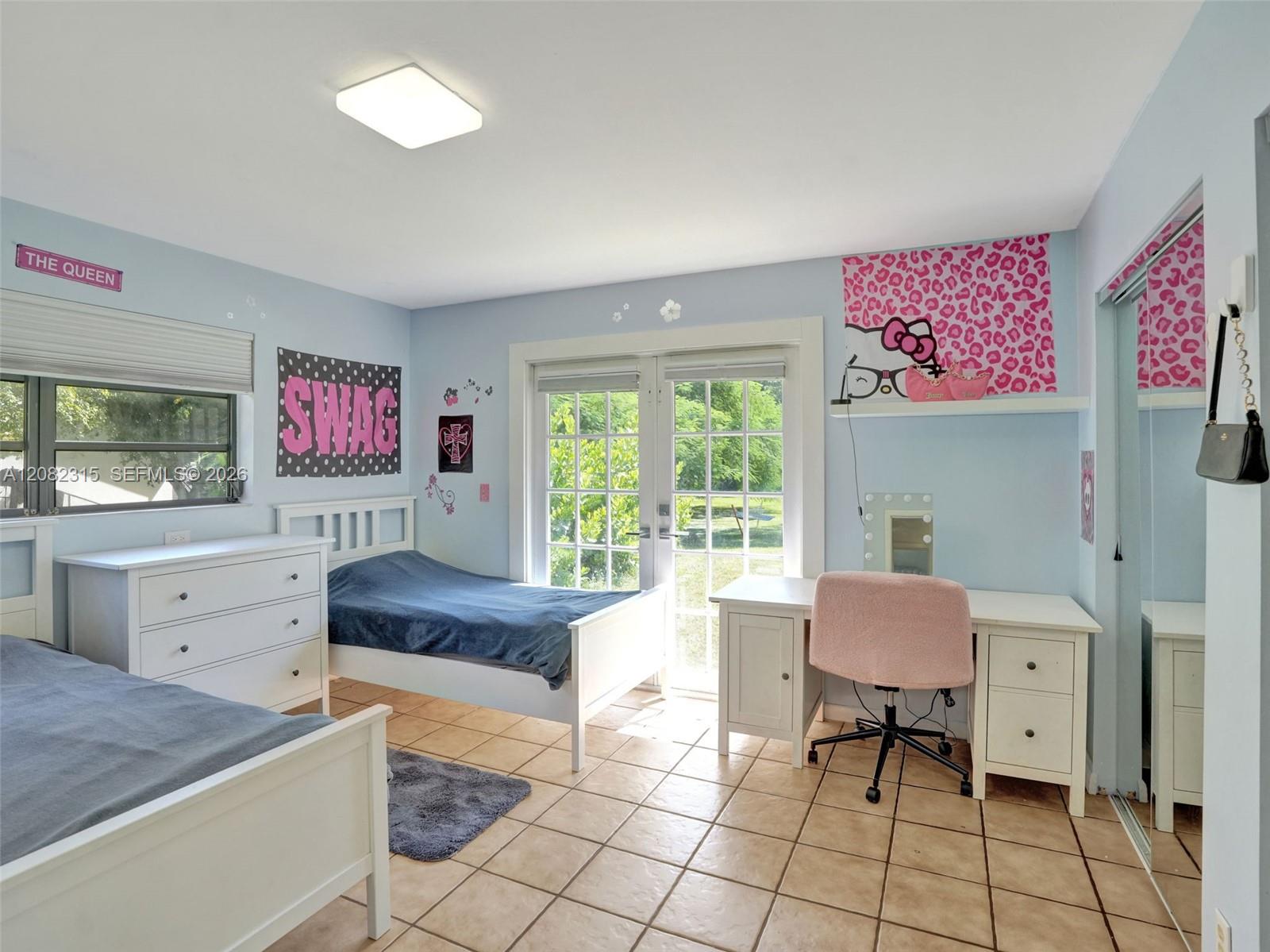 Ceramic tile flooring, glass-paneled double doors, mirrored closet doors, and a flush-mount overhead light fixture