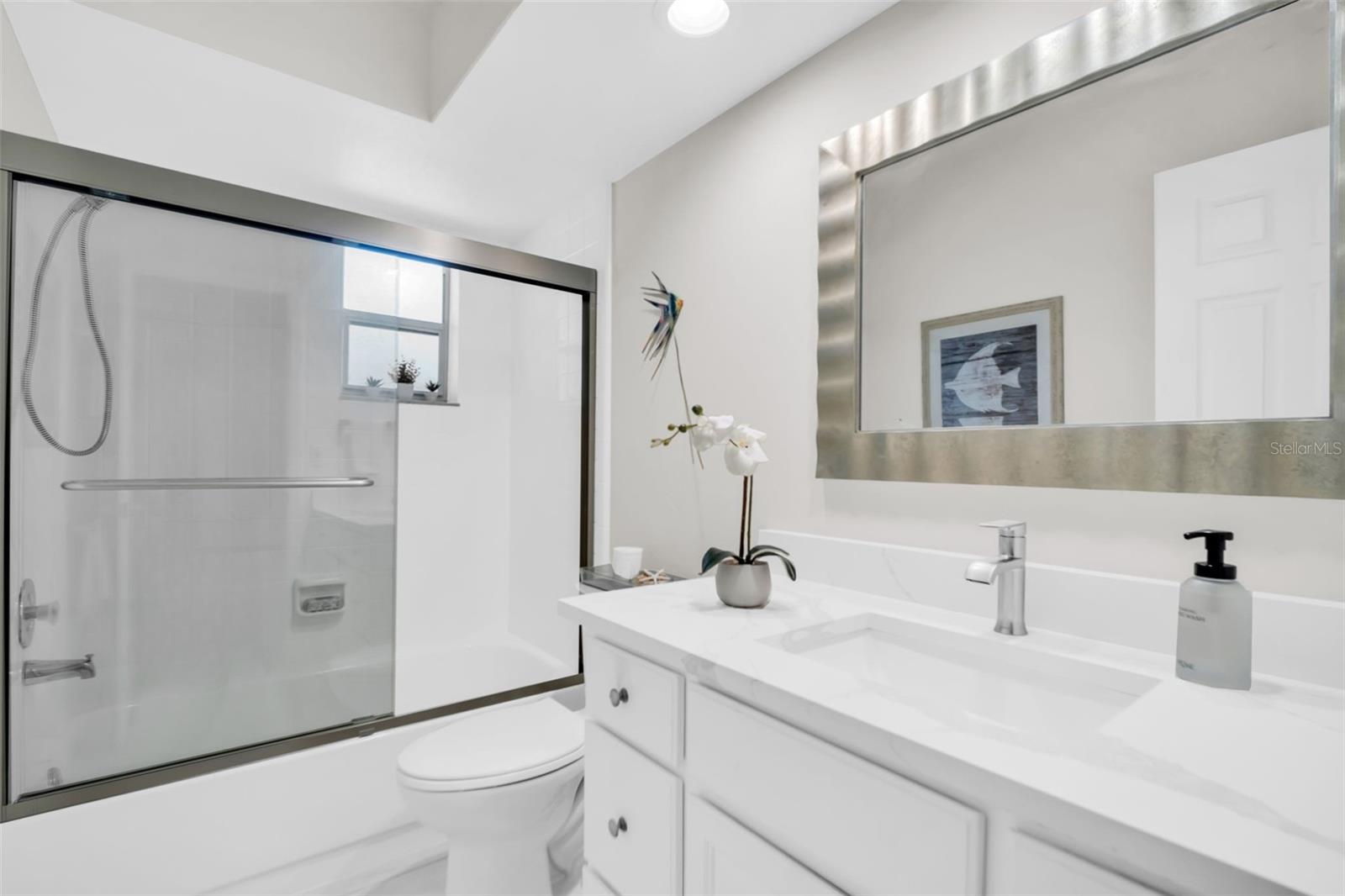 Beautifully updated hall bath with a new stone top vanity, fixtures, mirror, recessed lighting, and tub/shower combo~