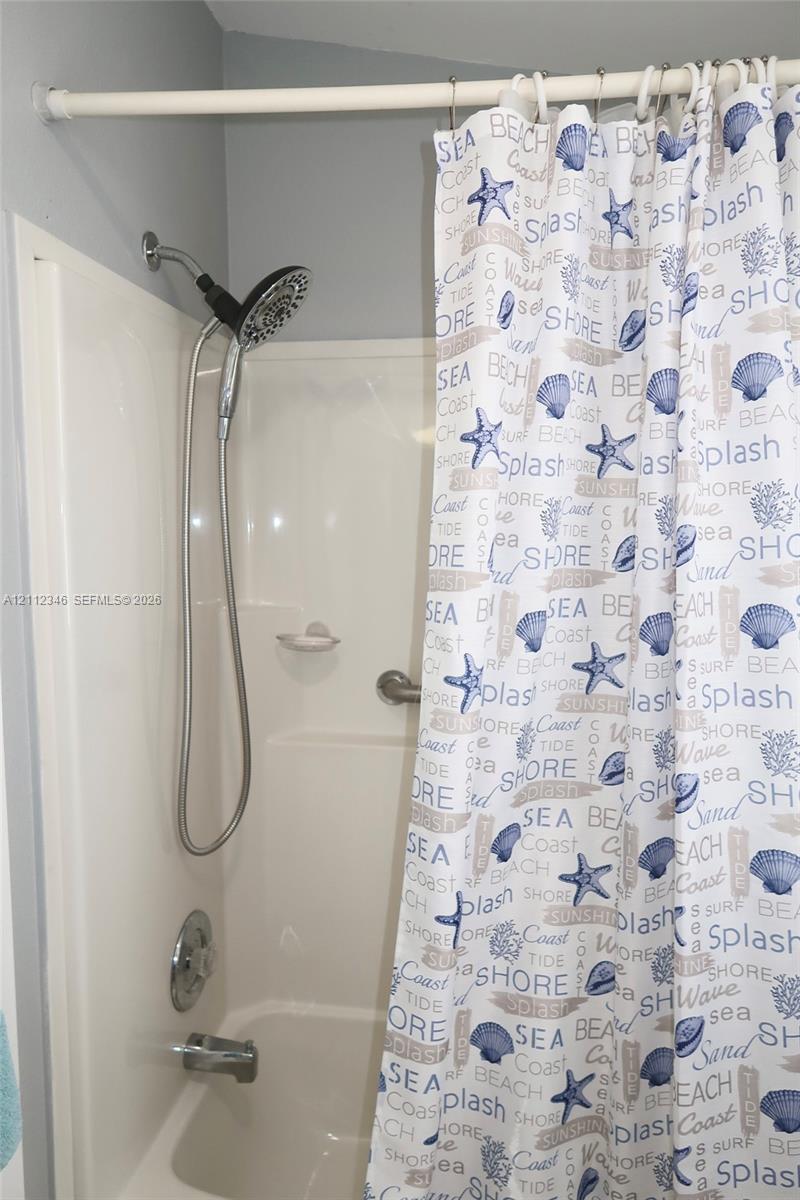 Bathtub and shower combination with a molded composite surround, integrated soap dish, chrome-finished multi-setting handheld shower head, and chrome 
