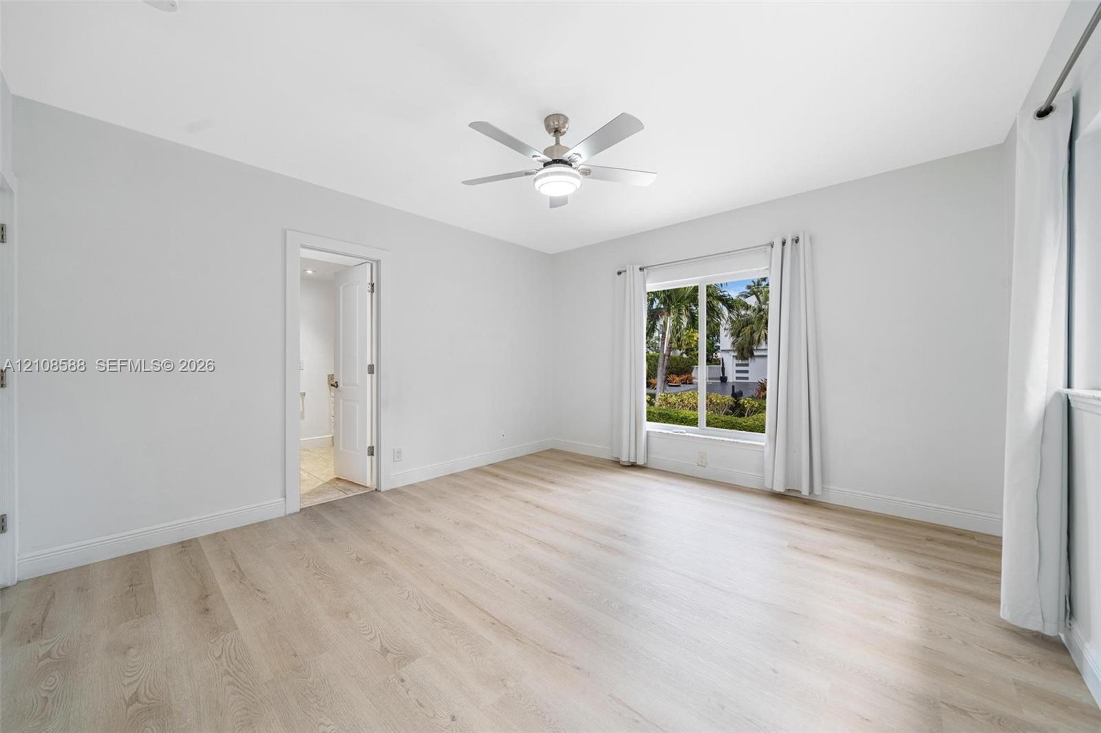 2nd Bedroom - Neutral-toned room featuring wood-finish flooring, a white ceiling fan with integrated lighting, and a large window