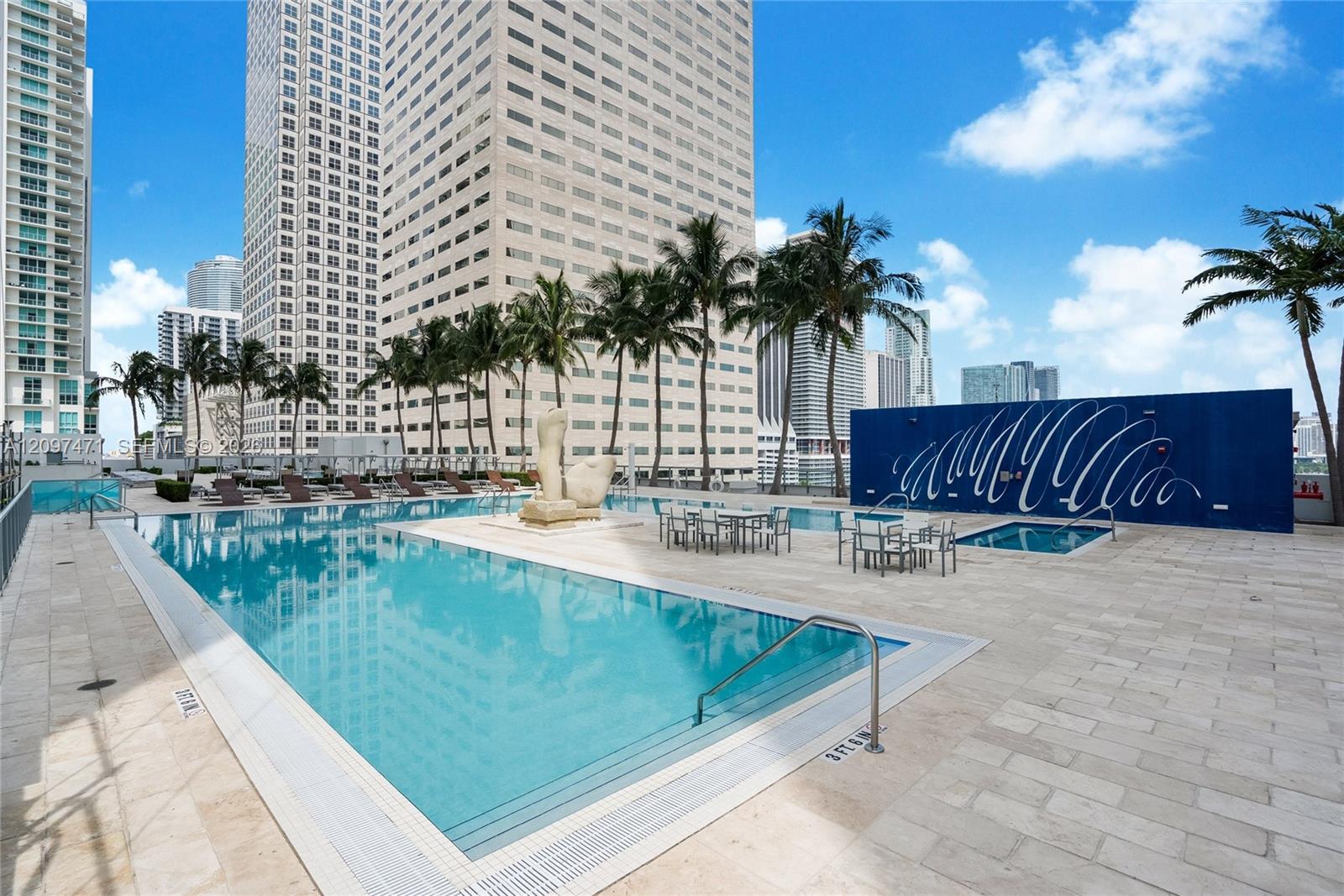 Outdoor swimming pool with built-in spa, stone-tiled pool deck, and integrated decorative sculpture