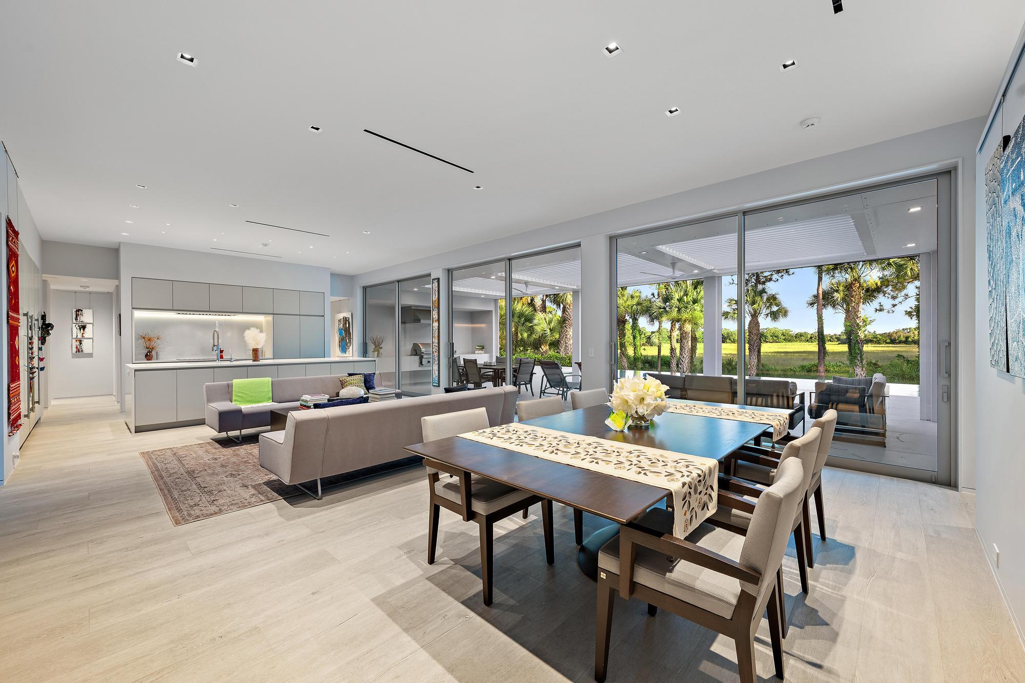 Open-concept living area featuring light wood-finish flooring, a contemporary kitchen with light cabinetry, and expansive sliding glass doors