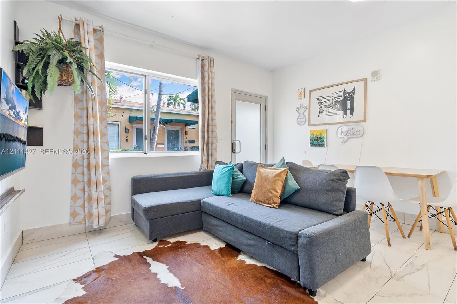 Living area featuring large-format tile flooring, recessed lighting, and a single-pane window with white trim