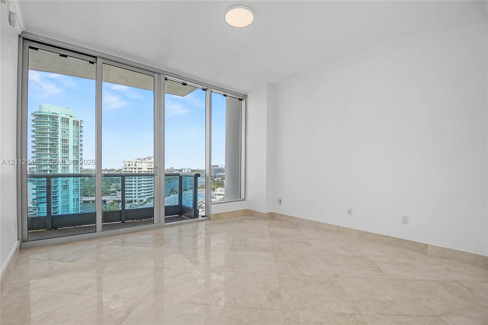 Floor-to-ceiling glass sliding doors, stone tile flooring, and a private balcony