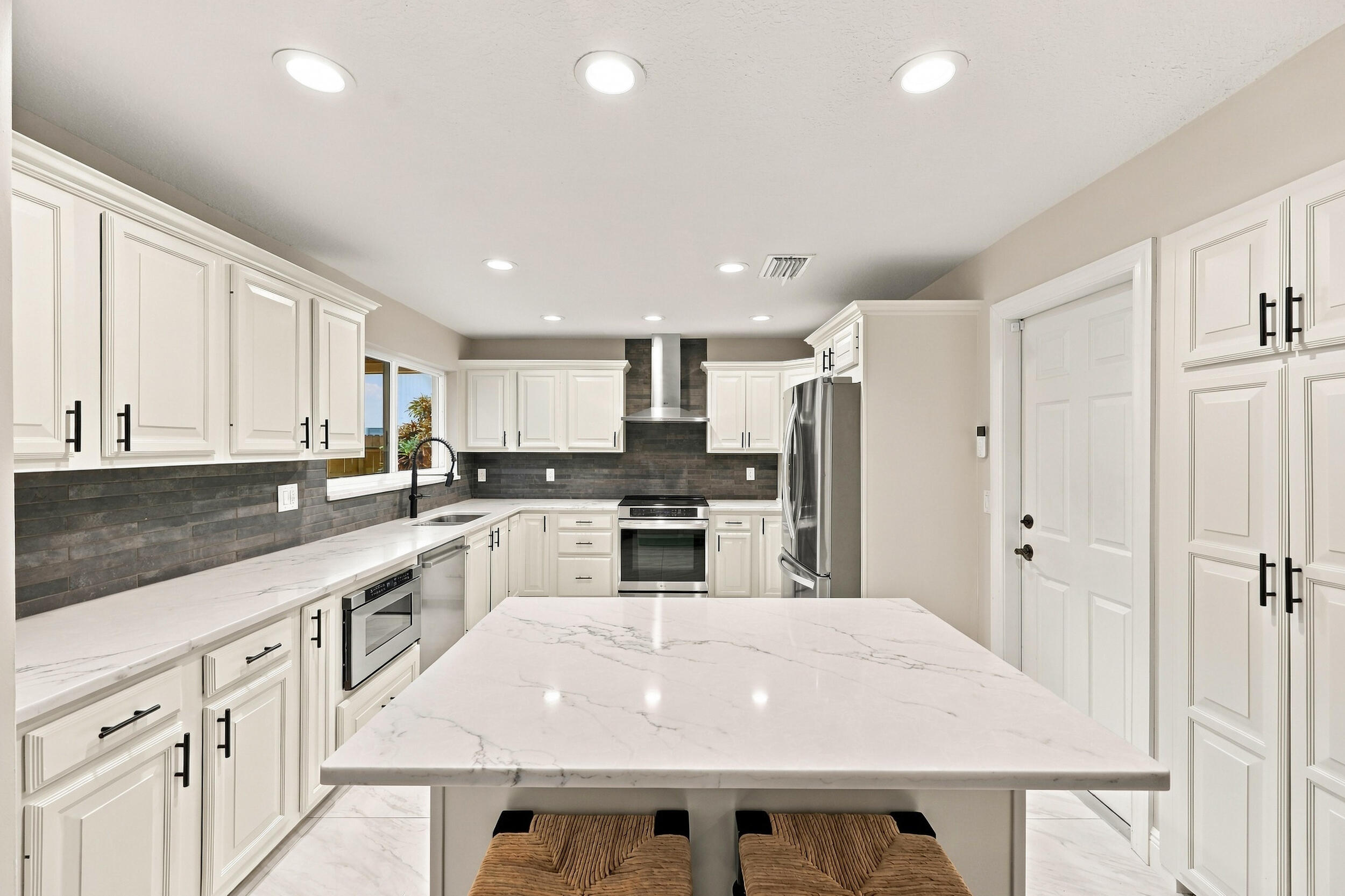 The impeccably upgraded kitchen offers white cabinetry, quartz countertops, stainless steel appliances, and a beautiful charcoal backsplash. There is