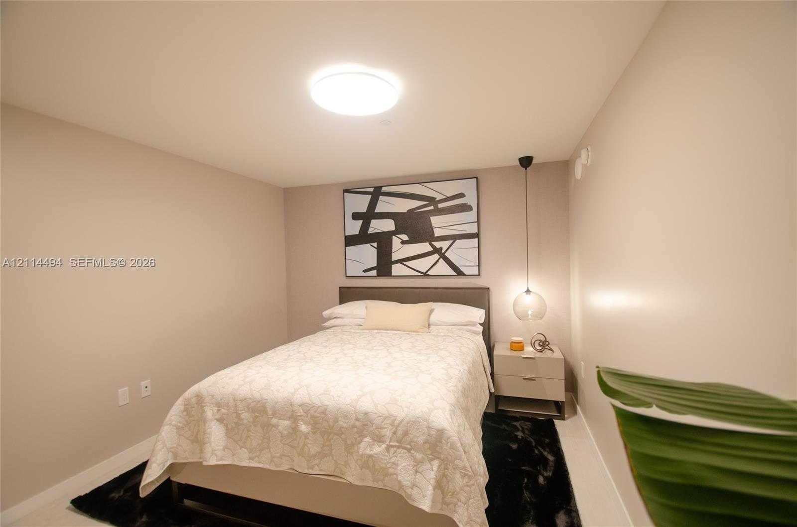 Neutral-toned room featuring a central flush-mount ceiling light and a suspended glass globe pendant light