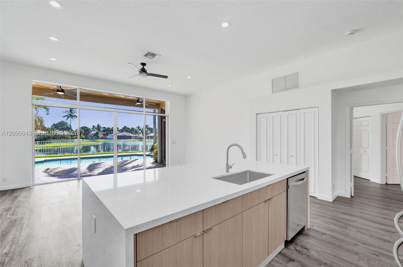 Kitchen featuring a center island with a quartz countertop, stainless steel undermount sink, built-in dishwasher, wood-finish cabinetry, and wood-fini