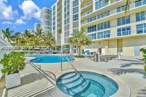 Outdoor terrace featuring a swimming pool, integrated spa, concrete deck surfacing, and mature palm trees