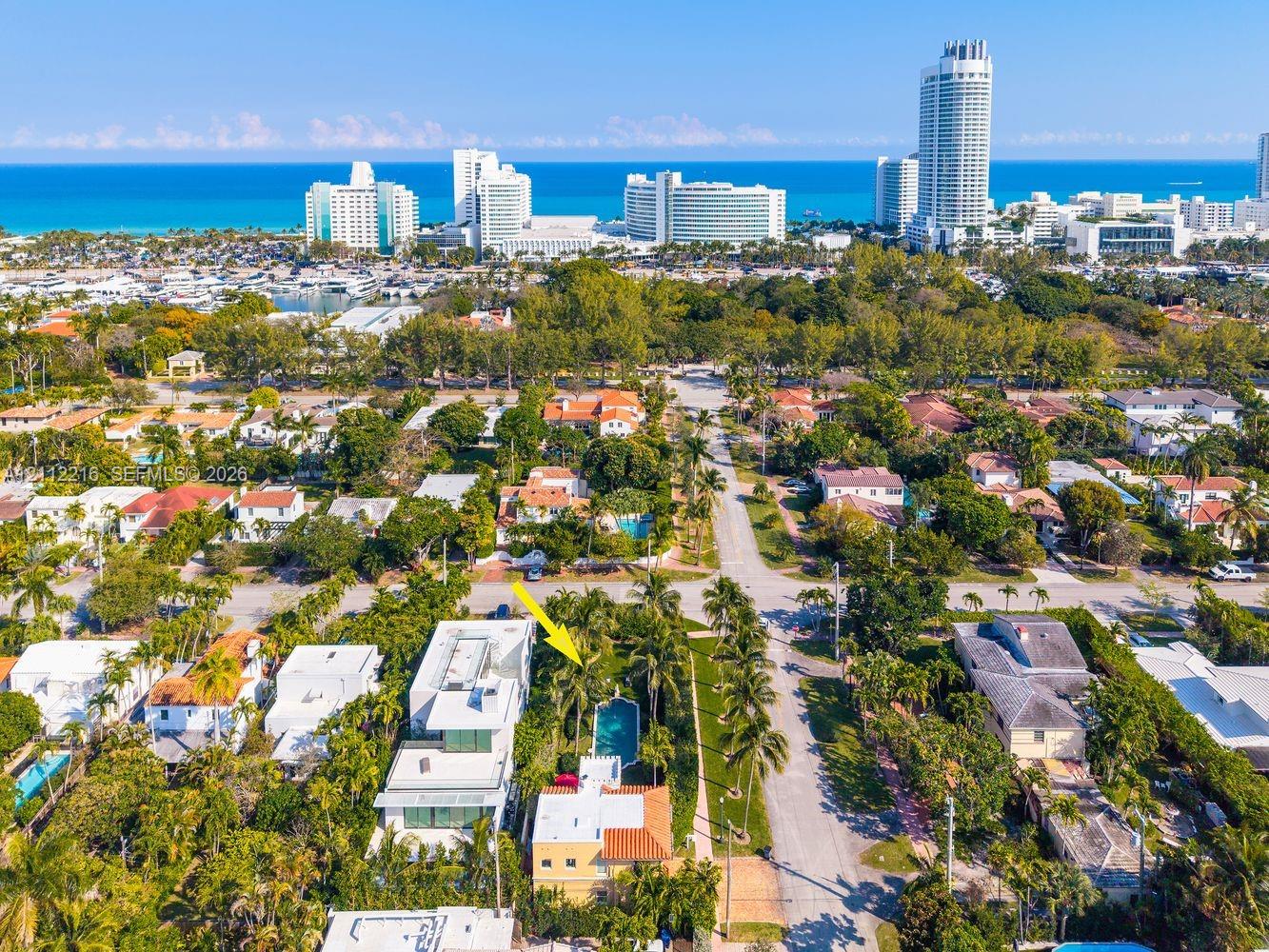 Aerial perspective featuring a multi-story residence with a red-tile roof and a private in-ground swimming pool surrounded by mature palm trees