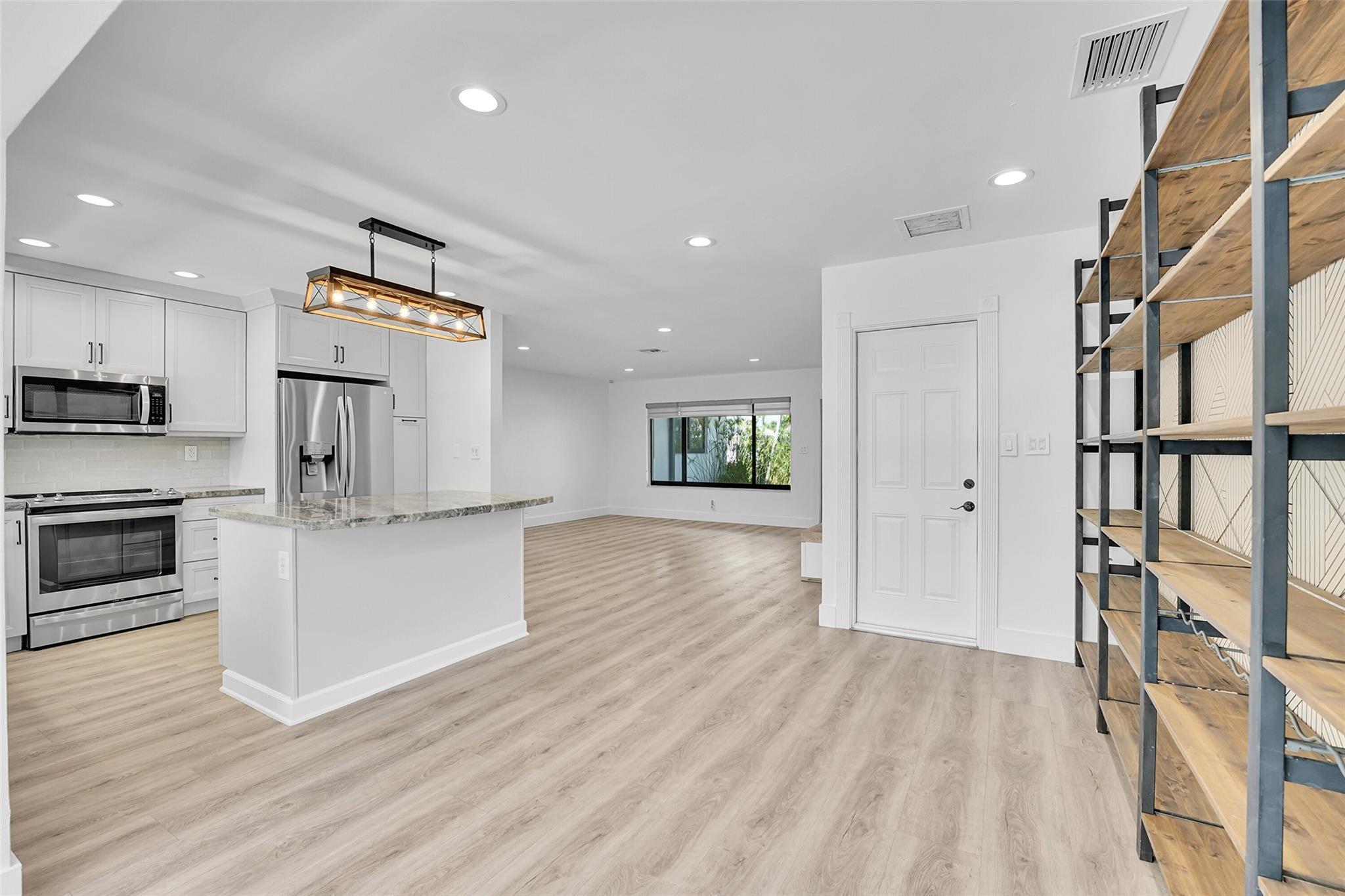 Kitchen featuring stainless steel appliances, light-toned cabinetry, and a central island with a stone countertop