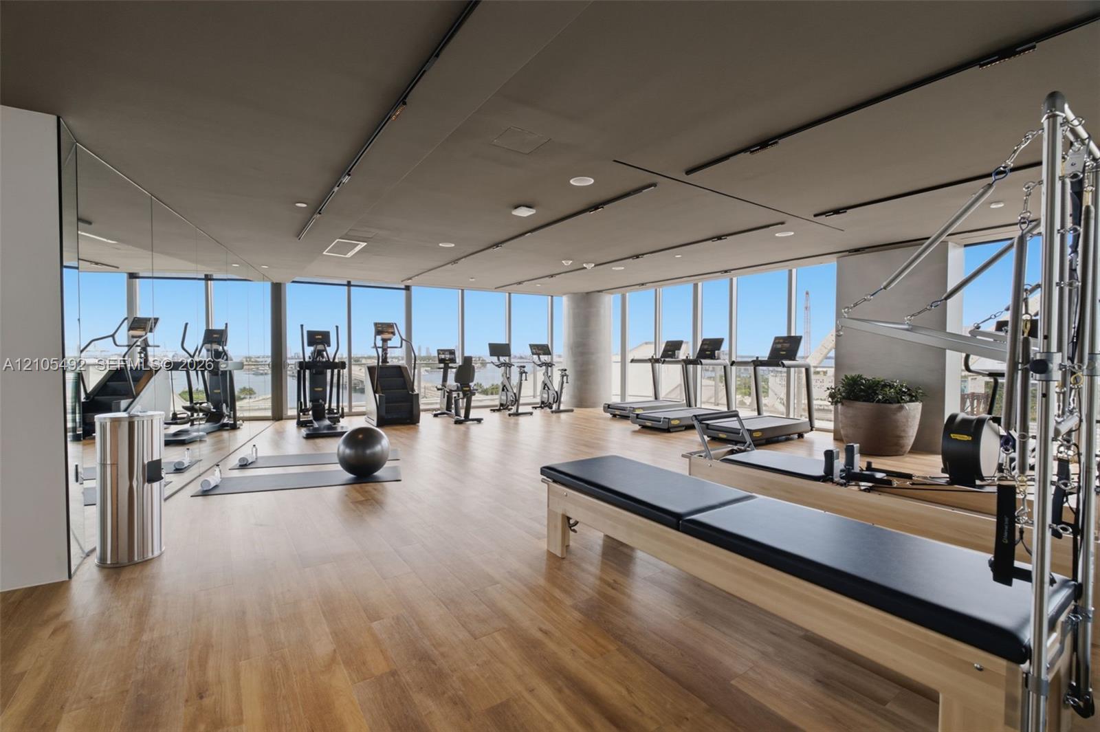 Fitness center featuring wood-finish flooring, floor-to-ceiling windows, and recessed lighting
