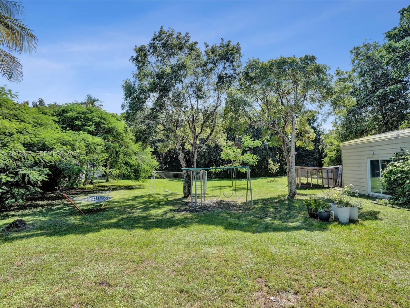 Expansive backyard featuring a large grass lawn, mature trees, and horizontal siding exterior