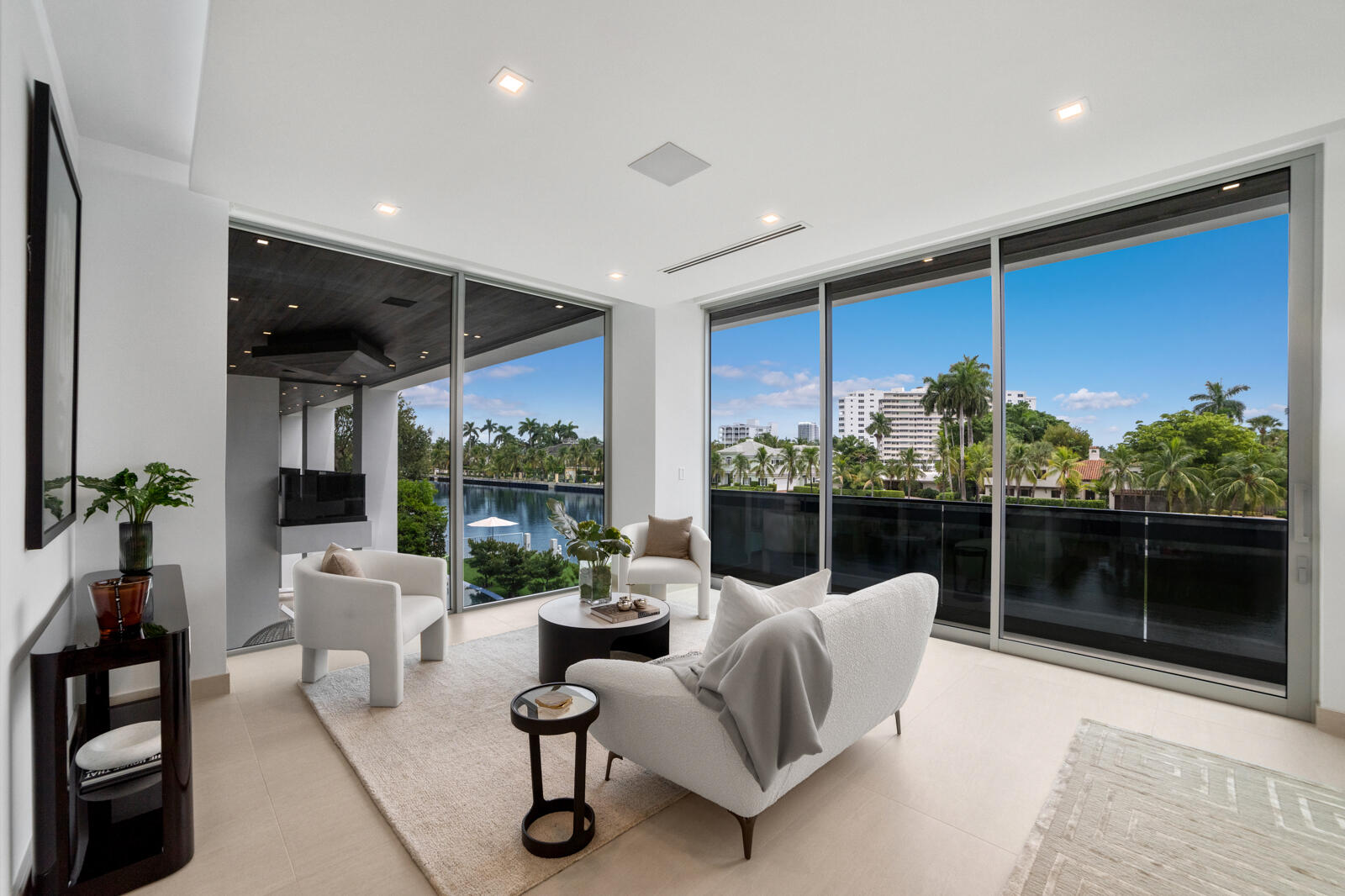 Waterfront sitting area within the primary suite, surrounded by walls of glass and opening directly to the private covered terrace.