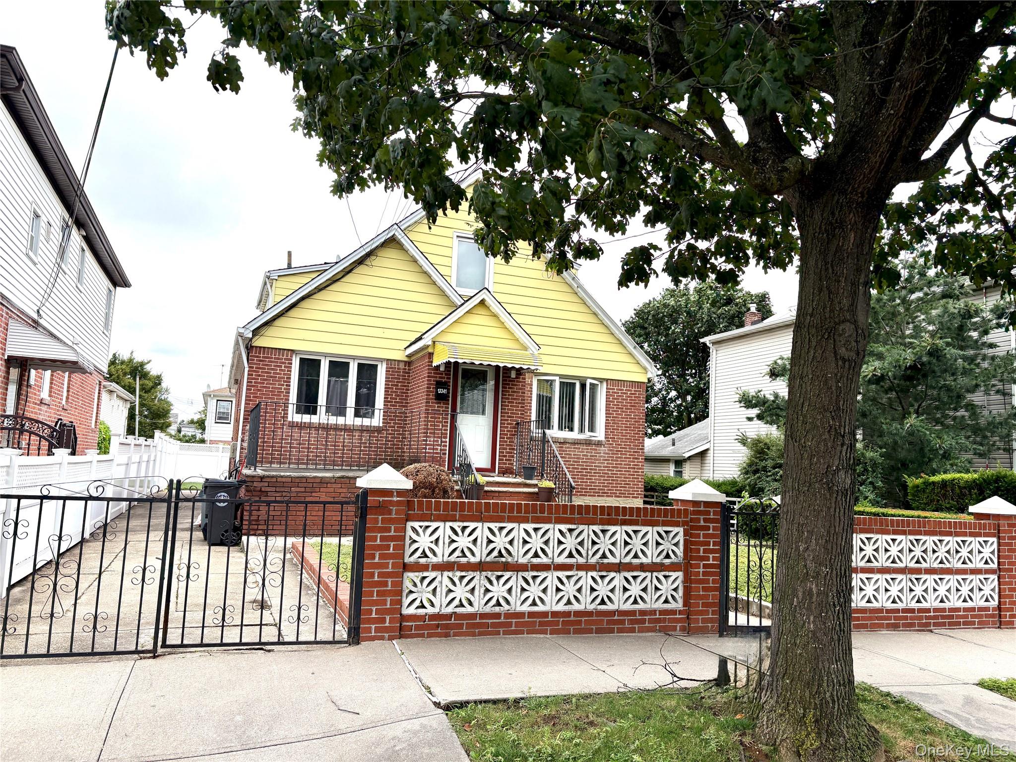 View of front of house with a gate, a fenced front yard, brick siding, and driveway
