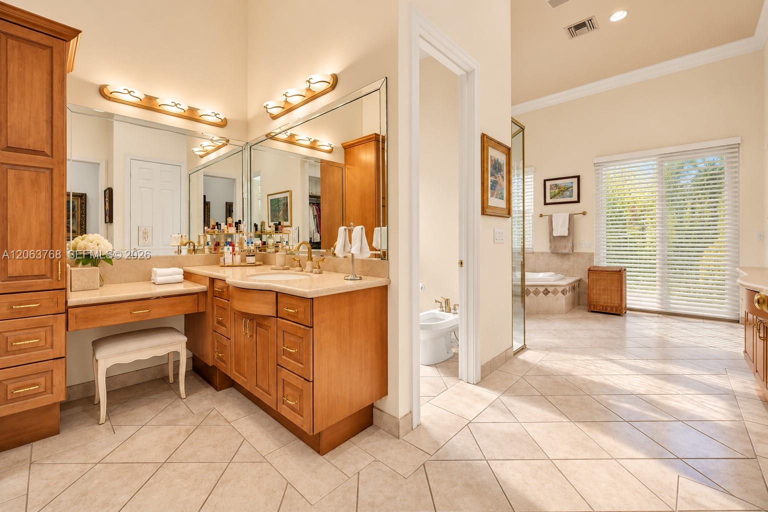 Bathroom featuring wood-finish cabinetry with a vanity station, stone-surfaced countertop, tile flooring, glass-enclosed shower, and a soaking tub