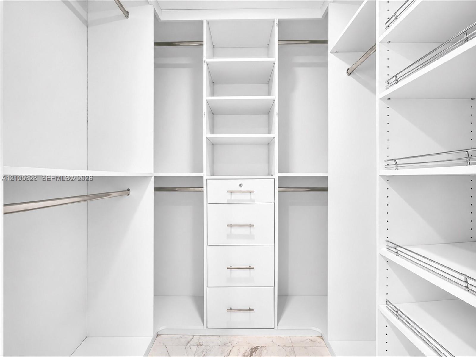 Luxurious custom-designed white closet system featuring generous hanging space, adjustable shelving, and built-in drawers with polished hardware for e