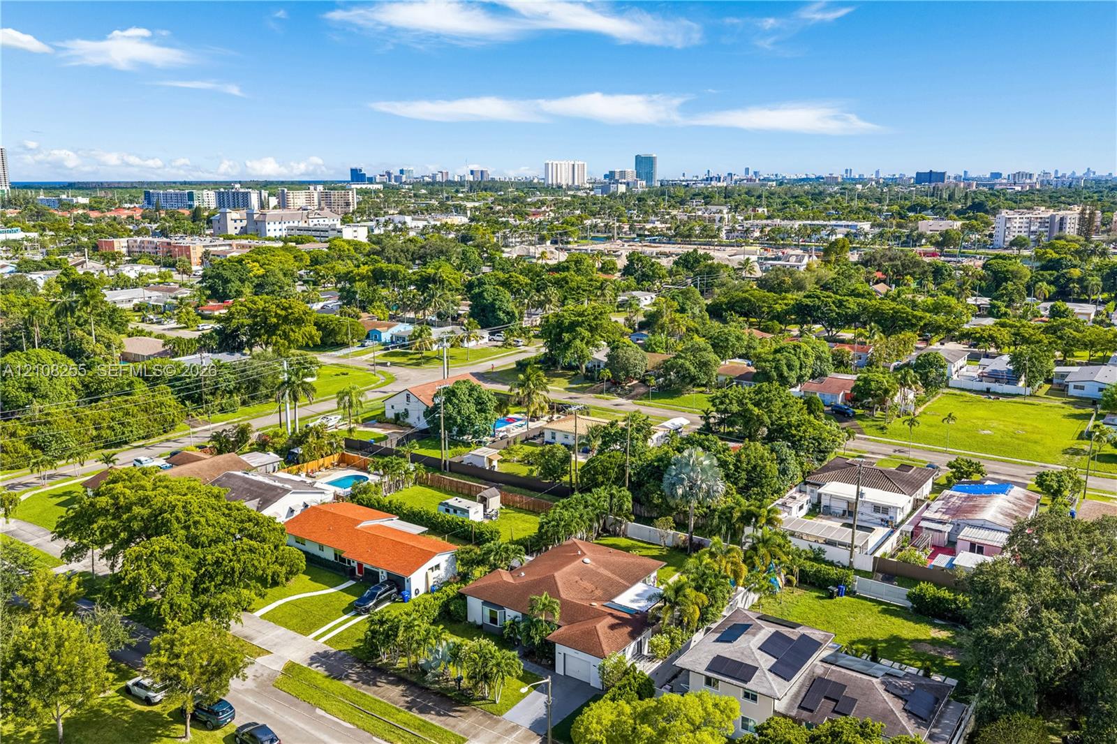 Aerial perspective of a suburban neighborhood featuring extensive mature tree canopy, residential lots with manicured lawns, and rooftops equipped wit