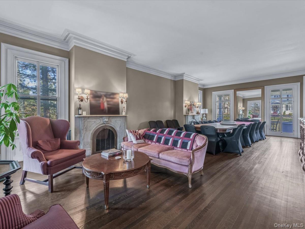 Living room with healthy amount of natural light, a premium fireplace, crown molding, and hardwood / wood-style flooring
