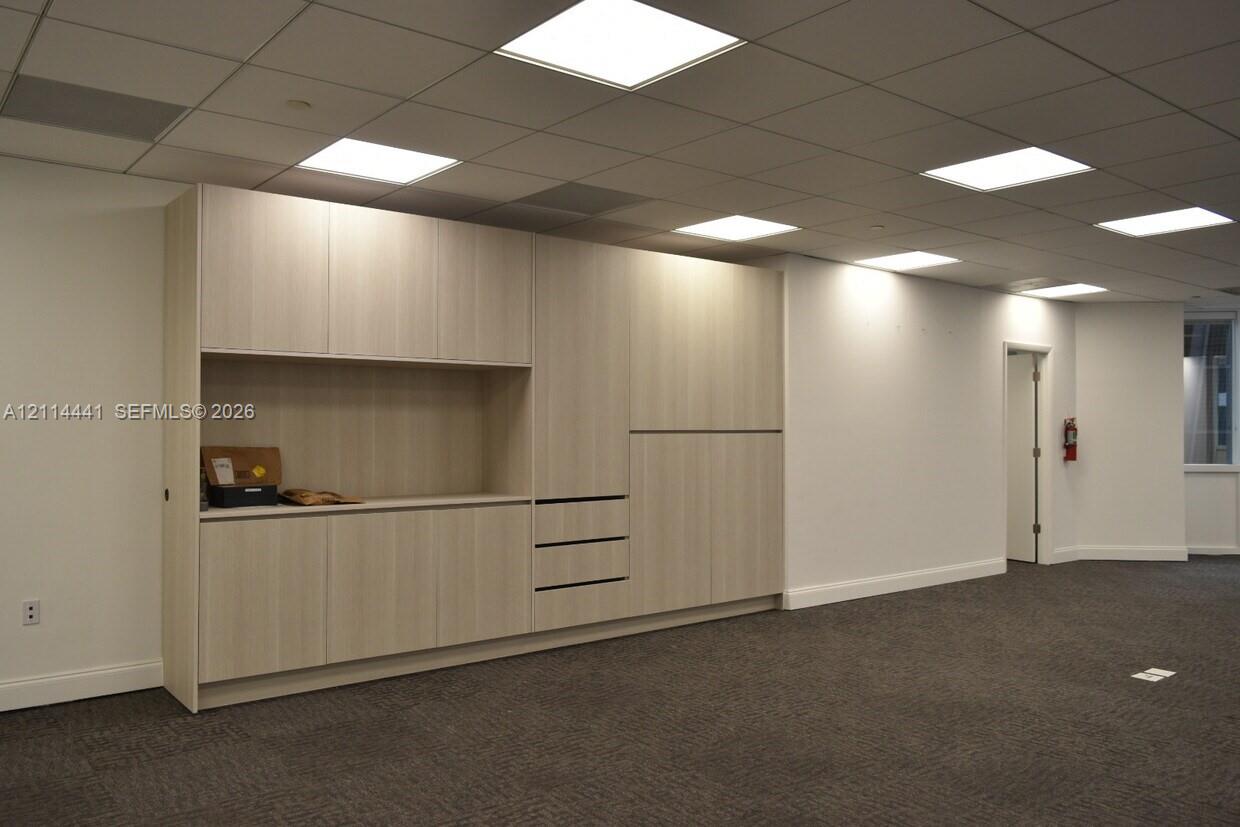 Built-in wall cabinetry featuring light wood-finish cabinetry, recessed drawer pulls, integrated shelving, and a drop-down counter surface under a dro