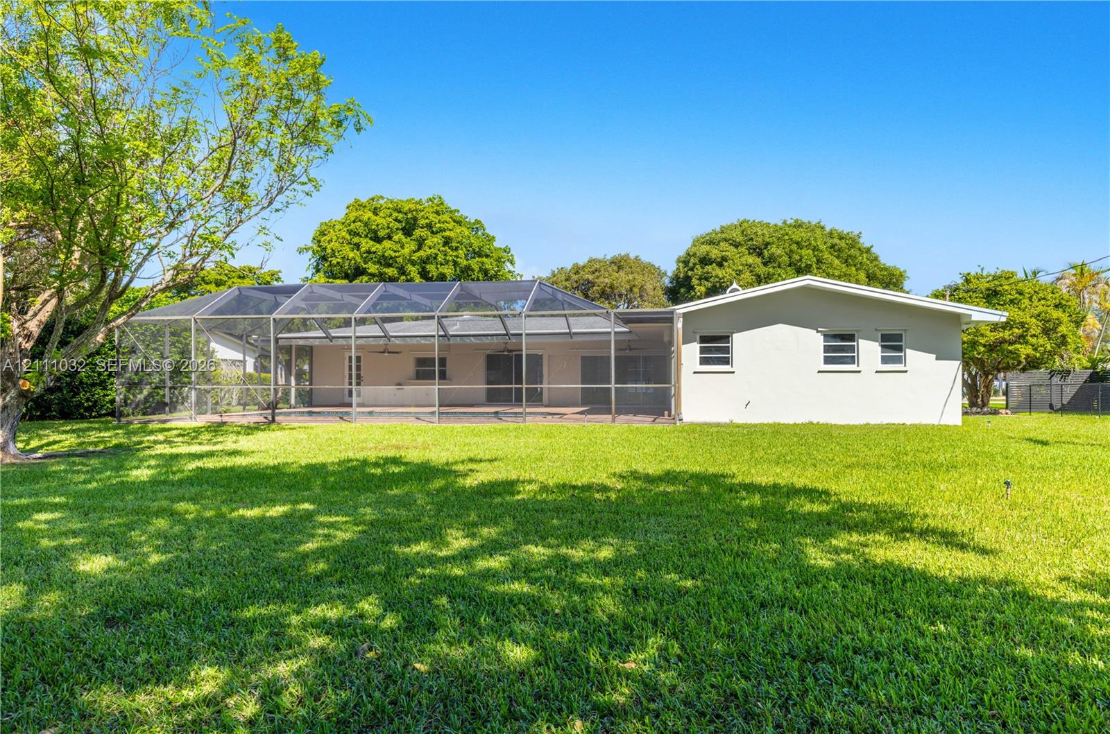Expansive lawn, screened-in patio area, and mature trees