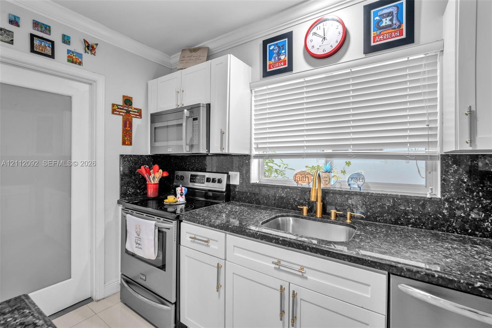 Open-concept interior featuring large-format tile flooring, recessed lighting, and a kitchen with white cabinetry, a center island with dark counterto