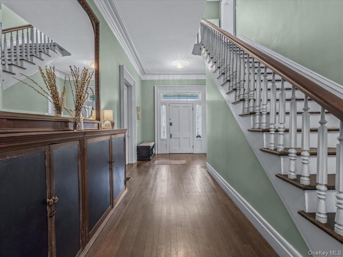 Entrance foyer featuring stairway, ornamental molding, and dark wood finished floors