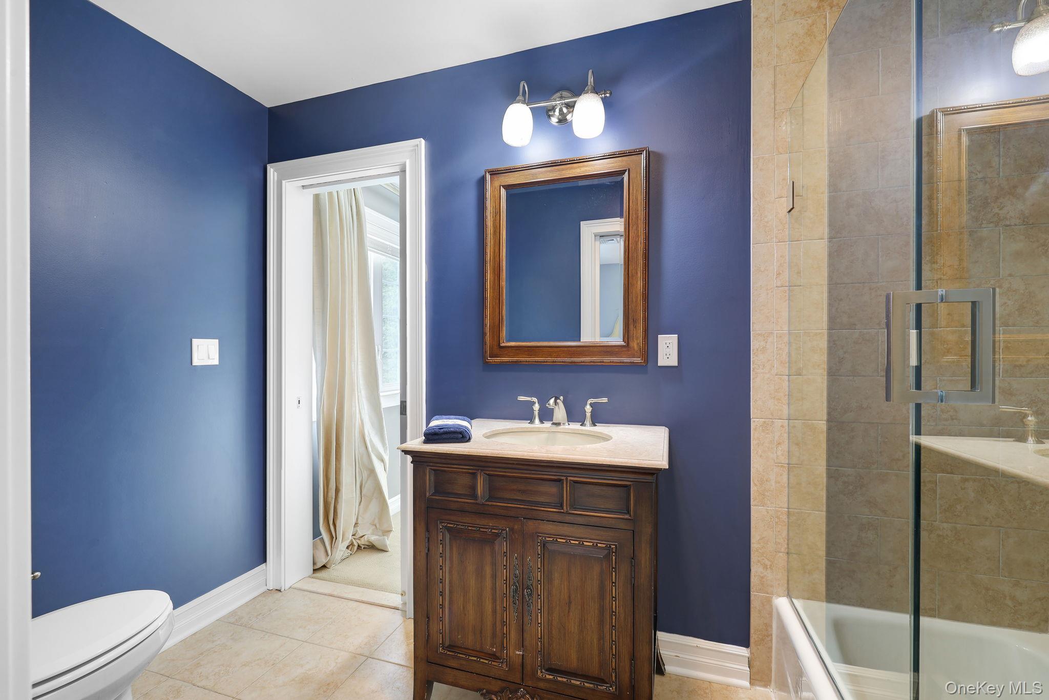 Jack and jill, bathroom hardwood vanity with a light-colored countertop, framed mirror, and a two-light fixture