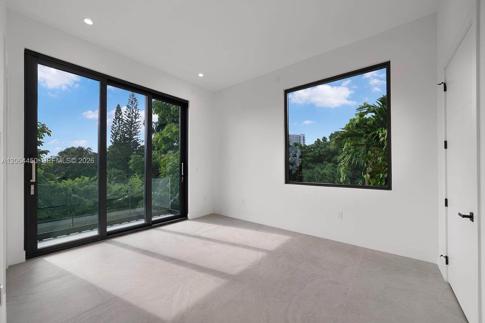 Large-format ceramic tile flooring, floor-to-ceiling sliding glass doors with black frames, oversized picture window, and recessed ceiling lighting