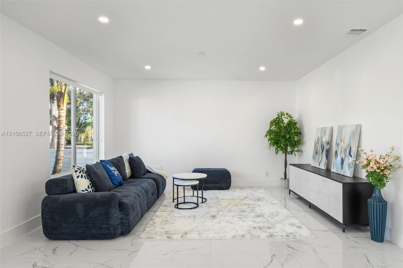 Neutral-toned interior featuring large-format tile flooring, recessed lighting, and a wide sliding glass door