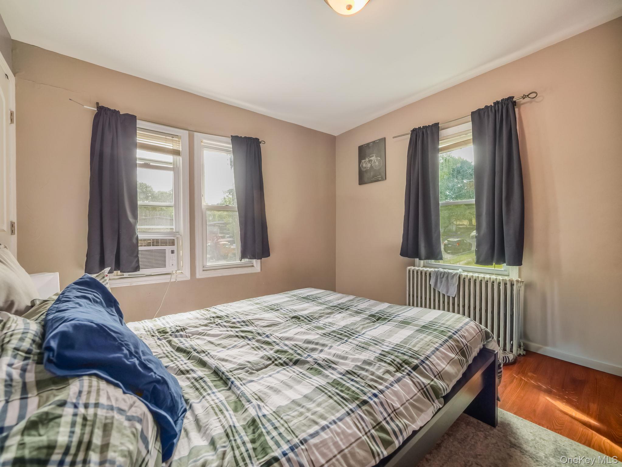 Bedroom featuring radiator heating unit, wood finished floors, and cooling unit