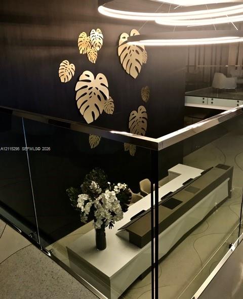 Glass and metal railing, dark paneled accent wall with metallic leaf-shaped wall art, and circular modern pendant light fixtures