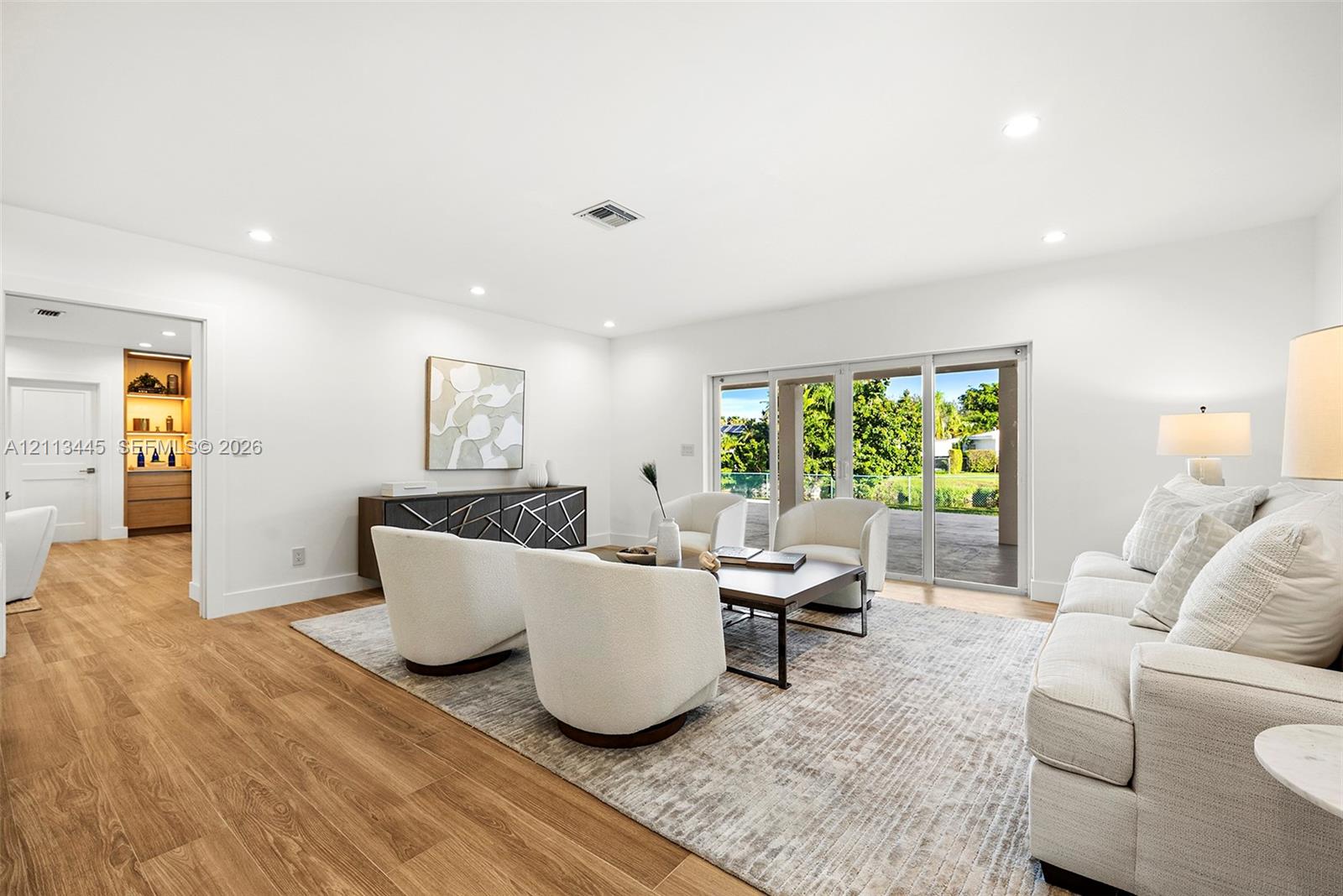 Living area featuring wood-finish flooring, recessed lighting, and expansive glass sliding doors